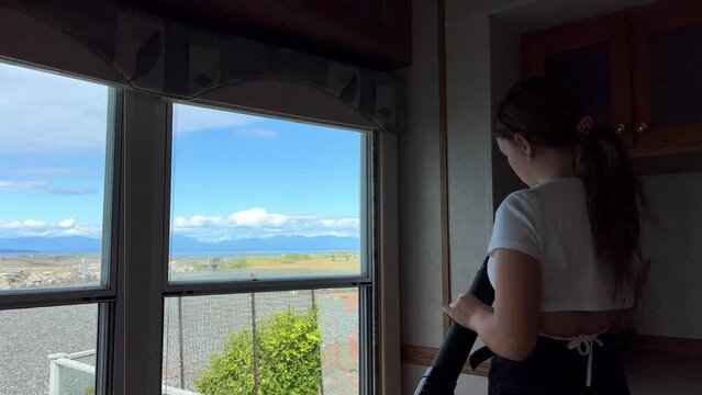 a teenager A girl stands in the trailer room and looks through a spyglass at the Pacific Ocean, looking for animals, the sea or ships, she is alone and bored but interesting Parksville beach