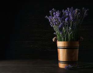 Wooden bucket with lavender on wooden background