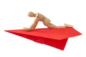 Wooden doll flying on a red paper plane