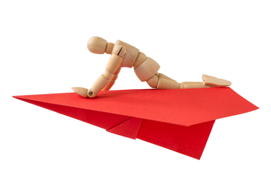 Wooden doll flying on a red paper plane