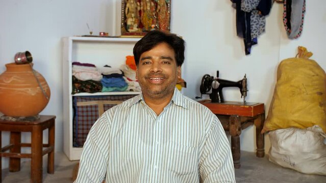 A portrait of a rural male with stubble - posing for the camera  poor man  daily wage worker. An Indian villager at home - rural household  cheerful  smiling man  poor single man 