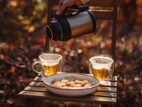 Drinking tea with cookies on wooden table. Cozy autumn mood scene in autumn park