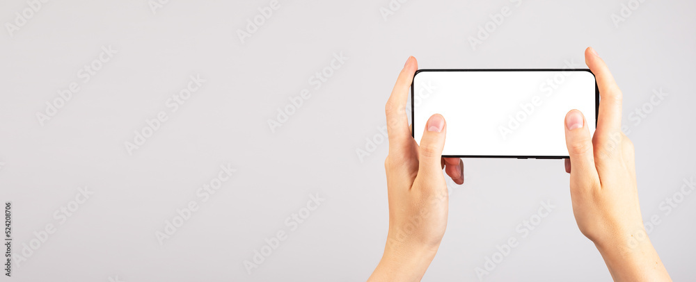 Poster Banner with hands holding phone mockup in horizontal position. Woman using smartphone for playing games. Mobile gaming. Android template with blank display. Copy space