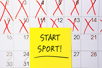 The phrase start sport written in black text on a yellow sticky note posted to a calendar page as a reminder. Close up of a personal agenda, top view. Motivational quote