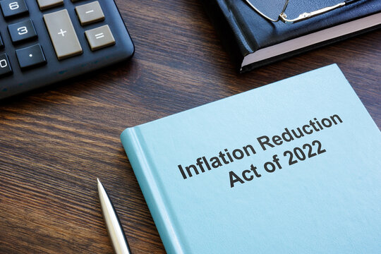 Book with The Inflation Reduction Act of 2022 near calculator and notebook.
