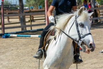 Little girl that rides a white pony during Pony Game competition at the Equestrian School