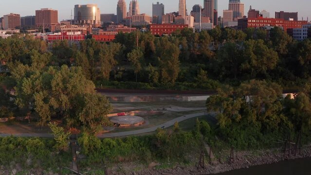 Low aerial shot tilting up from the Missouri River to the Kansas City skyline at sunset. 4K