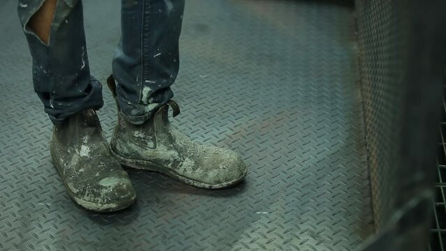 Workers steel cap boots with paint covered in spray booth bay area.