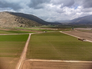 Farm fields with rows of green lettuce salad. Aerial view on agricultural valley Zafarraya with fertile soils for growing of vegetables, green lettuce salad, cabbage, artichokes, Andalusia, Spain