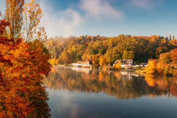 Beautiful autumn colours and reflections at a river on a foggy morning