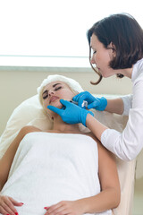 Fototapeta premium Lip augmentation and correction procedure in a cosmetology salon. The specialist makes an injection in the patient lips.