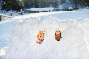Two funny happy children are playing in winter piles. A wonderful winter day in Lapland.