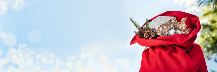 Happy New Year and Merry Christmas! Santa's red bag is filled with Christmas gifts for children. Christmas balls, toy snowman and gift box. Christmas and New Year background.