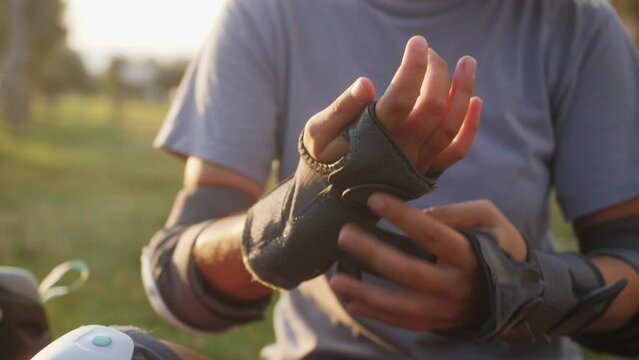 Woman putting on wrist guards and gloves at the skate park to protect. Sport outdoor.