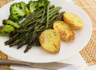 lean dish of cooked fried inflorescences of broccoli, asparagus growth and baked potatoes and Provencal herbs