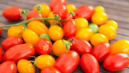 ripe appetizing yellow and red cherry tomatoes on wooden table