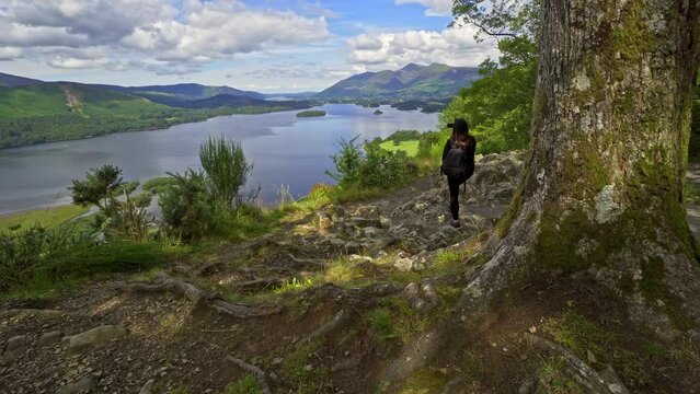 Woman female taking a photograph on a mobile phone View across Derwentwater in the English Lake District looking towards the town of Keswick with Skiddaw behind. Photo is taken from Surprise View