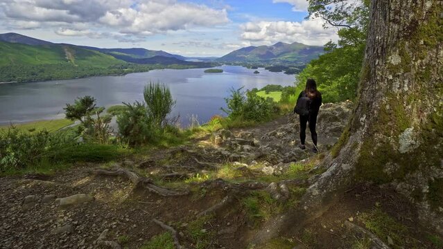 Woman female taking a photograph on a mobile phone View across Derwentwater in the English Lake District looking towards the town of Keswick with Skiddaw