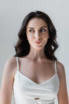 Portrait Of Sly Woman In White Top Isolated On Grey.