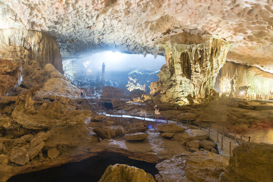 Tourist taking picture of giant rock formation shaped like horse with a long-sword linked to the legend of Thanh Giong inside Sung Sot Cave (Surprise Grotto) in Ha Long Bay