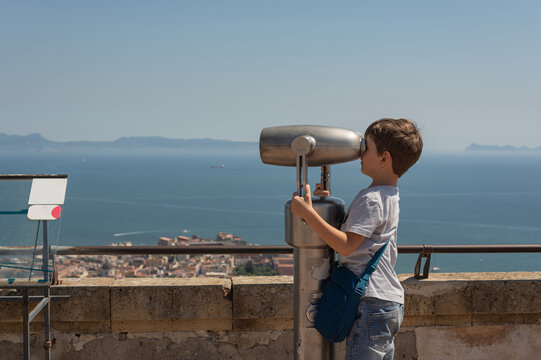 Children's tourism in Europe. Little boy with binoculars looking at the city of Naples, Italy. It looks at the mountains and Vesuvius.