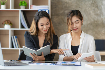 Two Asian business women working on a financial graph and a laptop.
in the presentation and review of the business plan Joint financial marketing strategies in the meeting room with new employees in t