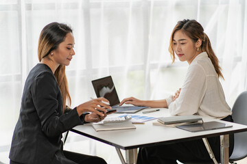 Two Asian business women working on a financial graph and a laptop.
in the presentation and review of the business plan Joint financial marketing strategies in the meeting room with new employees in t