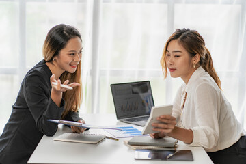 Two Asian business women working on a financial graph and a laptop.
in the presentation and review of the business plan Joint financial marketing strategies in the meeting room with new employees in t