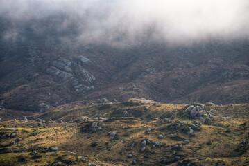 The fog dissipates and reveals a landscape of rocks and grasses in the Xistral