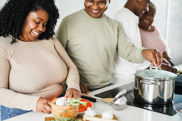 Happy black family cooking inside kitchen at home - Focus on girl face