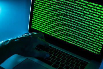 Hand typing on laptop keyboard, green numbers on display. Hacker forcing the system. Programmer writes the code. Technology communication, informatics, security protection, hacker, cyber crime concept © Fabio Principe