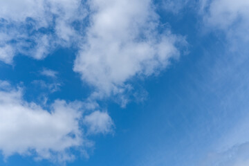 Blue sky background with white fluffy cumulus clouds. Panorama of white fluffy clouds in the blue sky. Beautiful vast blue sky with amazing scattered cumulus clouds.