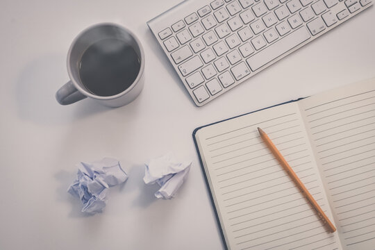 Desktop view with keyboard, pencil, agenda and books. Table with objects for smart working or homeschooling. Organization, remote work, study, creativity, production, indecision, confusion concept.