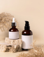 Cosmetic bottles on beige stones near dry pampas grass on light beige close up. Labels Mockup