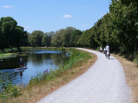 A man on a stand-up paddle on a small canal. July 2022, Blain, France. 