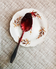 a spoon stained with jam lies on a plate