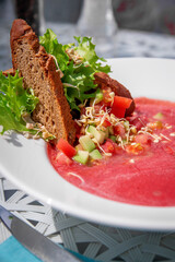 Summer cold watermelon smoothie gazpacho soup, sea blue background with avocado slices, watermelon, lime and herbs