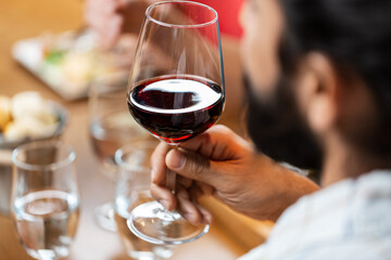 leisure, drinks and people concept - close up of man with glass drinking red wine at restaurant