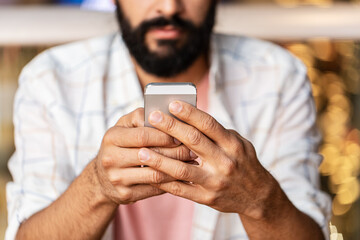 people, technology and communication concept - close up of man with smartphone at restaurant