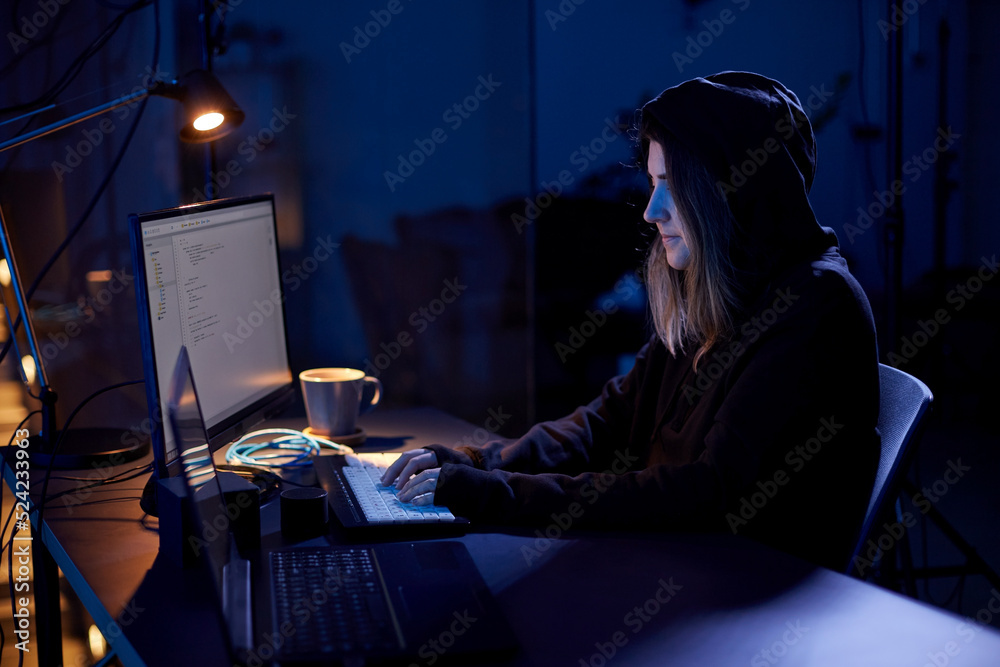 Wall mural cybercrime, hacking and technology concept - female hacker in dark room writing code or using comput