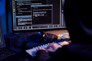 cybercrime, hacking and technology concept - close up of hacker in dark room writing code or using...