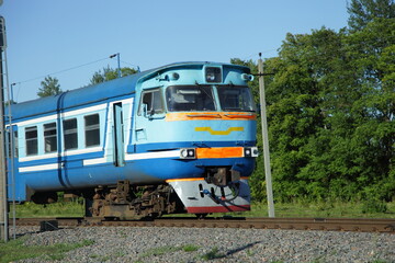 Obraz premium Old Russian suburban passenger train on countryside forest background drive on one way railway at summer day