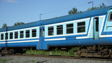 Old Russian suburban passenger blue train on one way railroad at summer day