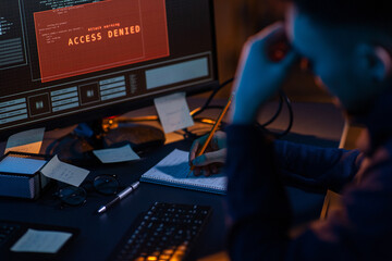 cybercrime, hacking and technology concept - close up of male hacker in dark room writing to...