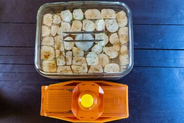 Borner vegetable cutter and Supra electric dryer, top view. Apple chips sliced in a vegetable cutter. Apple in fruit holder. Preparation for drying apple chips. Krasnodar, Russia - August 07, 2022