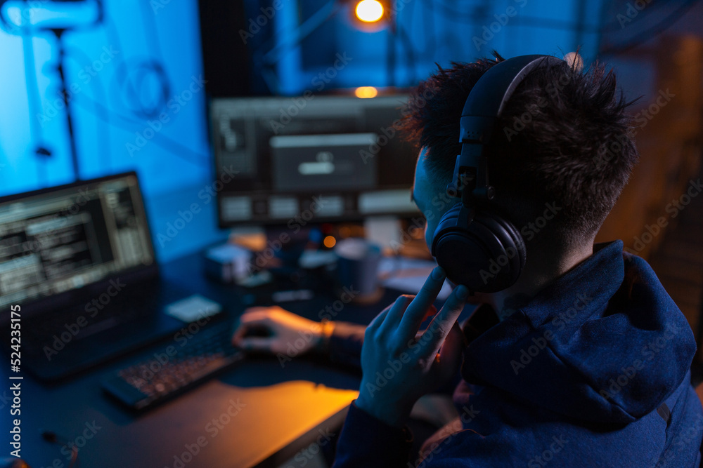 Poster cybercrime, hacking and technology concept - close up of male hacker in dark room writing code or us