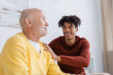 Cheerful african american man hugging blurred granddad at home.