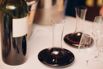 the waiter pours elite red wine into the decanter on the table in the restaurant.