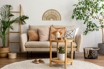 Scandinavian and cozy interior of living room with design beige sofa, pillows, side tables, plants,...