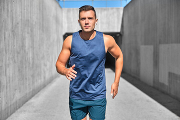 Naklejka na ściany i meble fitness, sport, training and lifestyle concept - young man with wireless earphones running outdoors